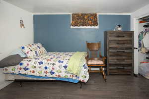 Bedroom with wood finished floors and a closet