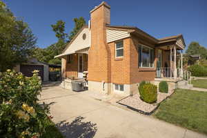 View of property exterior featuring an outbuilding, a chimney, a detached garage, brick siding, and concrete driveway
