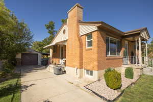 View of home's exterior with an outdoor structure, concrete driveway, a chimney, a garage, and brick siding