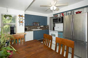 Kitchen featuring dark countertops, appliances with stainless steel finishes, blue cabinetry, light tile patterned floors, and tasteful backsplash