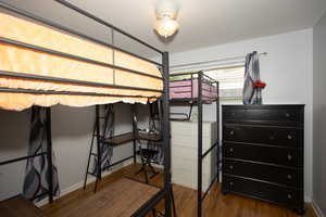 Bedroom with wood finished floors and a garage