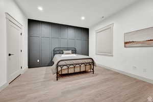 Bedroom with light wood-type flooring, recessed lighting, and a decorative wall
