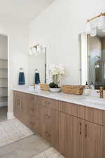Bathroom featuring double vanity, a spacious closet, and light tile patterned flooring