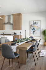 Kitchen featuring light wood-style flooring, wall chimney range hood, recessed lighting, brown cabinetry, and modern cabinets