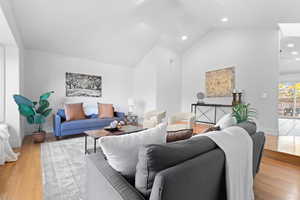Living room with high vaulted ceiling, light wood-style flooring, and recessed lighting