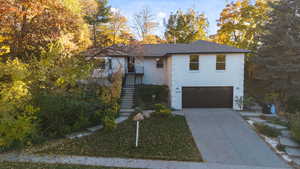 View of front facade featuring stairway, driveway, a garage, and brick siding