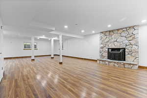 Below grade area with a stone fireplace, light wood finished floors, and recessed lighting