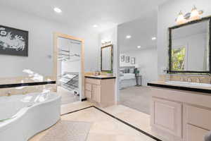 Full bath featuring ensuite bathroom, inlaid floor details, recessed lighting, two vanities, and a garden tub