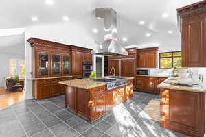Kitchen featuring stainless steel appliances, recessed lighting, island range hood, an island with sink, and light stone counters
