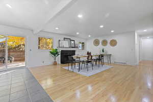 Dining space with recessed lighting, light wood-type flooring, beam ceiling, and a fireplace