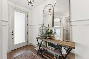 Gorgeous Entryway highlighted with a tall and inviting 8 ft front door, warm white oak laminate finished floors and wainscotting accents.