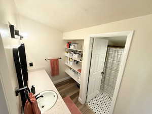 Bathroom with a textured ceiling, double vanity, a shower with shower curtain, and light wood-style floors