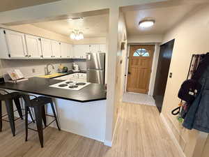 Kitchen featuring dark countertops, a textured ceiling, white cabinetry, light wood-style floors, and freestanding refrigerator