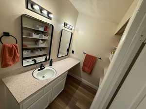 Bathroom with dark wood-style floors, vanity, and a textured ceiling