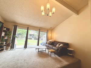 Living area featuring a textured ceiling, carpet flooring, and a chandelier
