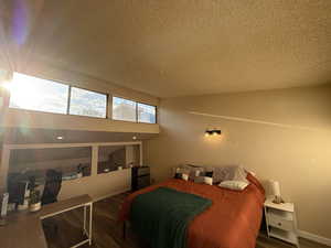 Bedroom featuring a textured ceiling, dark wood finished floors, and fridge