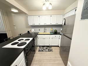 Kitchen with stainless steel appliances, dark countertops, a breakfast bar, white cabinetry, and decorative backsplash