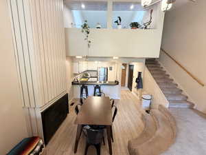 Dining space with light wood finished floors, a towering ceiling, and stairway