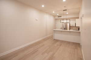 Kitchen with recessed lighting, a kitchen breakfast bar, white cabinetry, light countertops, and hanging light fixtures