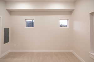 Basement featuring light colored carpet and electric panel