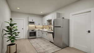 Kitchen with appliances with stainless steel finishes, light wood-style flooring, recessed lighting, decorative backsplash, and light countertops