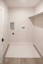 Laundry area with hookup for a washing machine, light wood-style floors, and electric dryer hookup