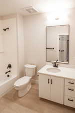 Bathroom with vanity, shower / bath combination, light wood-style floors, and a textured ceiling