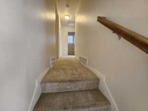 Stairs with carpet flooring, a textured wall, and attic access
