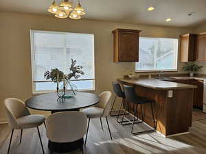 Dining area with light wood finished floors, a textured ceiling, recessed lighting, and a chandelier