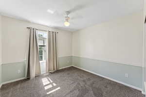 Carpeted spare room featuring baseboards and a ceiling fan
