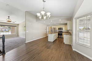 Kitchen with open floor plan, a kitchen island, a chandelier, appliances with stainless steel finishes, and decorative light fixtures