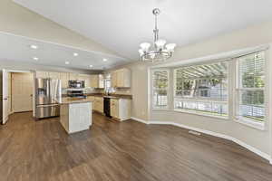 Kitchen with a kitchen island, pendant lighting, lofted ceiling, a chandelier, and stainless steel appliances