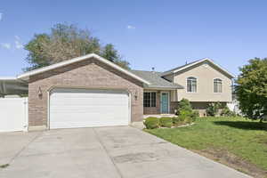 Tri-level home with driveway, an attached garage, and brick siding