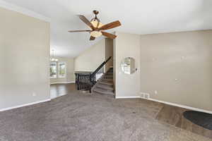 Unfurnished living room with carpet flooring, stairs, high vaulted ceiling, ceiling fan, and a chandelier