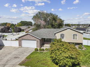 View of front of home with brick siding, an attached garage, driveway, and roof with shingles