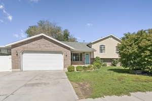 Tri-level home featuring driveway, an attached garage, and brick siding