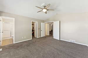 Unfurnished bedroom with a spacious closet, carpet flooring, lofted ceiling, connected bathroom, and ceiling fan