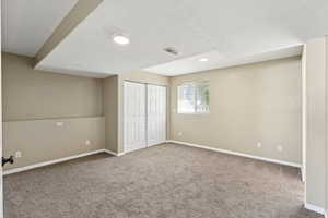 Unfurnished bedroom with a textured ceiling, light carpet, and a closet