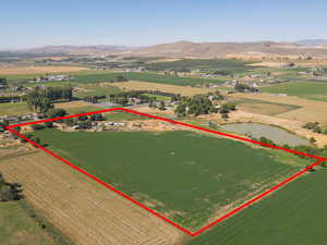 Aerial view of sparsely populated area with property parcel outlined, rows of crops, and a water and mountain view