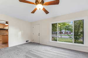 Unfurnished living room with a ceiling fan, light colored carpet, and light tile patterned floors