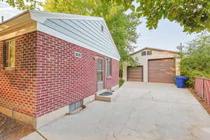 View of property exterior featuring an outdoor structure, brick siding, and a detached garage