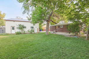 View of green lawn with an outbuilding and a patio area