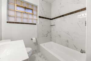 Bathroom featuring shower / bathtub combination, marble look tiles, and vanity