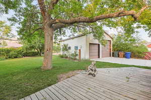 Deck featuring a yard, a garage, and an outbuilding