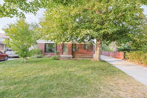 View of property hidden behind natural elements with brick siding