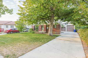 View of front of house with brick siding, a front lawn, driveway, and a garage