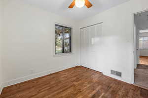 Unfurnished bedroom featuring dark wood finished floors, a closet, and a ceiling fan