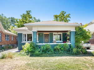 Bungalow-style home with brick siding, a front lawn, and covered porch