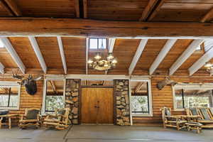 Unfurnished living room with wood ceiling, plenty of natural light, and a chandelier