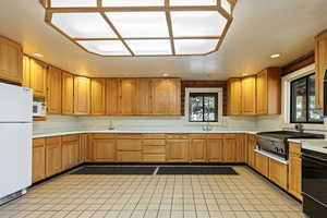 Kitchen with light countertops, white appliances, recessed lighting, and brown cabinetry